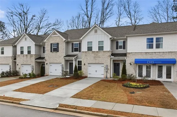 a view of a white house with large windows next to a yard