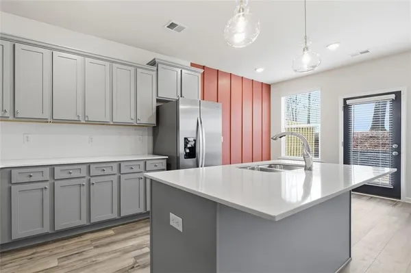 a large kitchen with kitchen island a large counter top a sink stainless steel appliances and cabinets