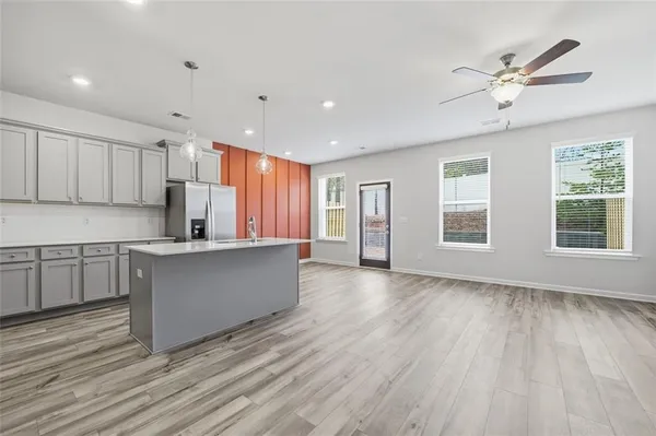 a kitchen with stainless steel appliances granite countertop a refrigerator a sink dishwasher a stove and white countertops with wooden floor