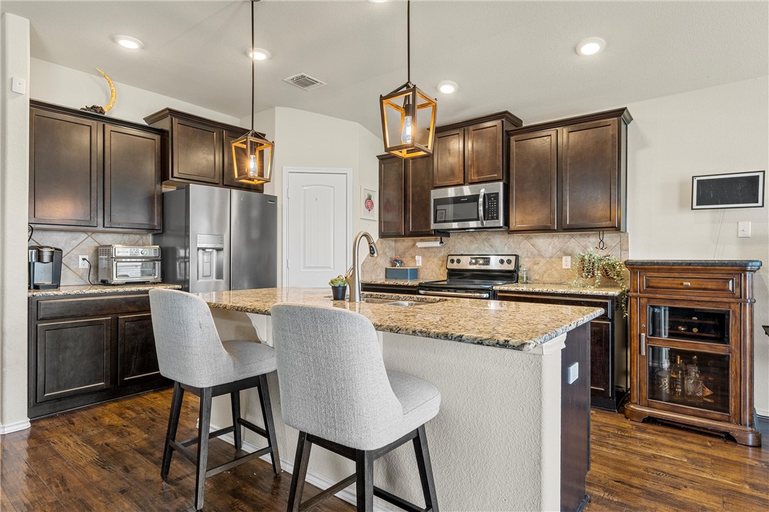 11220 Haviture Way Waco, TX 76708 - Photo 6 of 23 a kitchen with stainless steel appliances granite countertop a stove refrigerator a oven a sink with island and chairs