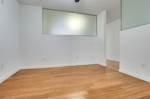 a view of an empty room with wooden floor and windows