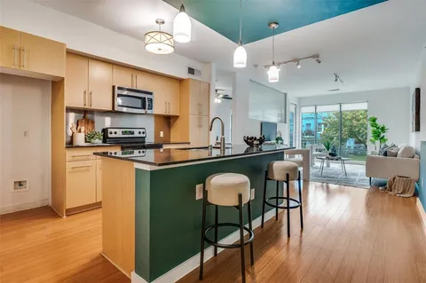 a kitchen with stainless steel appliances granite countertop a stove top oven a sink dishwasher a dining table and chairs with wooden floor