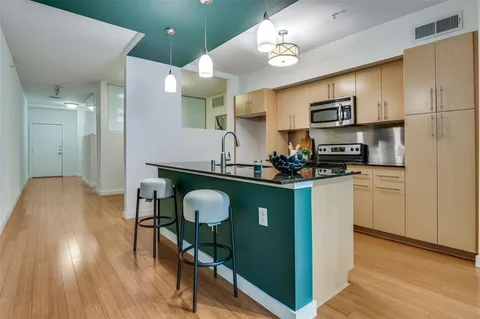 a kitchen with stainless steel appliances a dining table chairs stove and cabinets