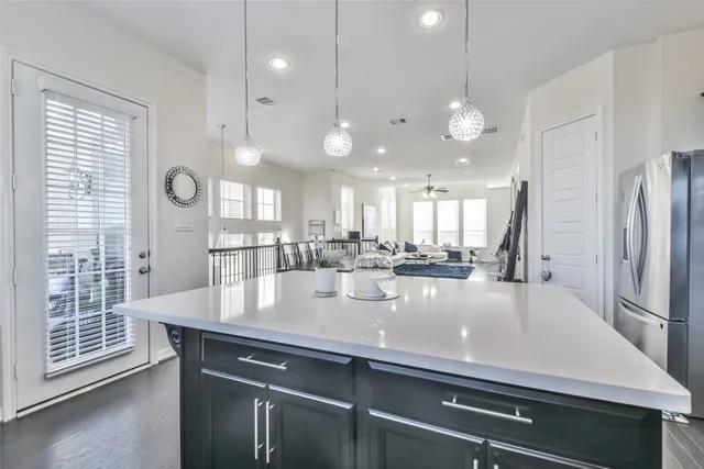 a view of a room with kitchen island stainless steel appliances wooden floor and windows