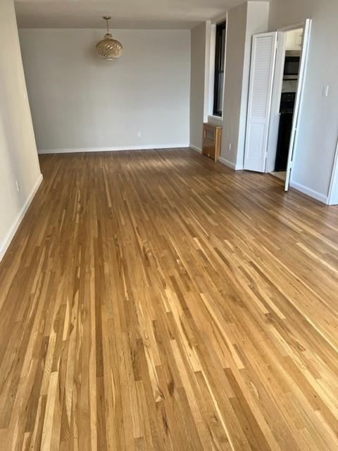 200 Corbin Place, Unit 2H Brooklyn, NY 11235 - Photo 13 of 18 a view of an empty room with wooden floor