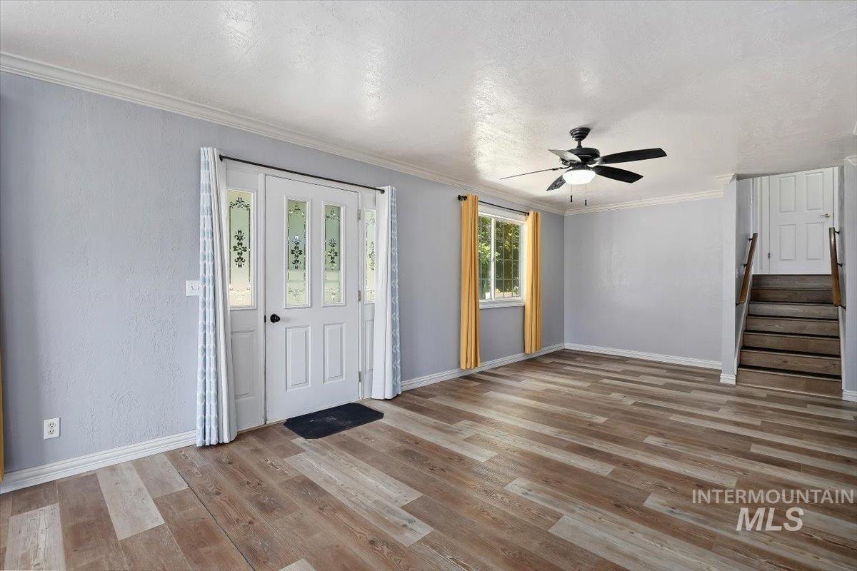 1940 Q Street Heyburn, ID 83336 - Photo 7 of 30 Wood-finish flooring throughout, featuring a paneled entry door with decorative glass inserts, a window with natural light, a ceiling fan, and staircase with wood railing