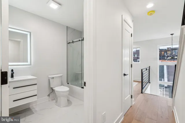 a view of a hallway with wooden floor and a bathroom
