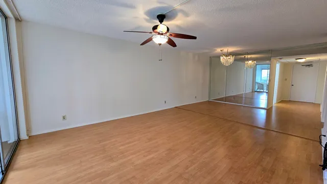 wooden floor in an empty room with a chandelier fan