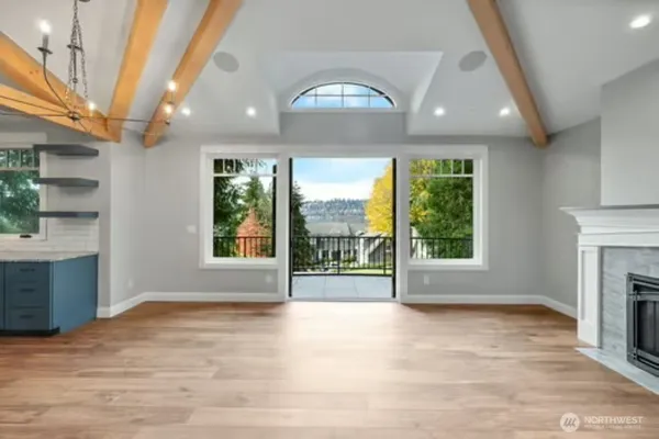a view of an empty room with wooden floor fireplace and a window