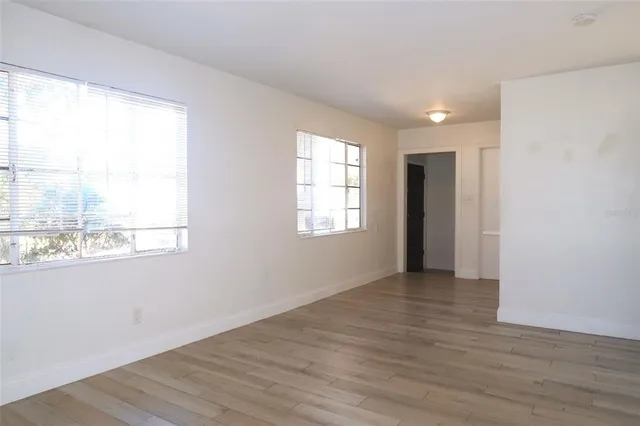 an empty room with wooden floor and windows