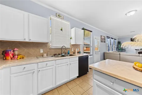 a kitchen with white cabinets and sink