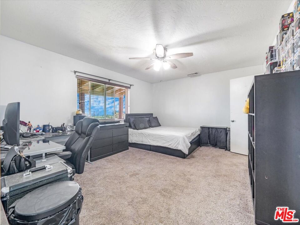 9446 Green Road Pinon Hills, CA 92372 - Photo 17 of 24 a spacious bedroom with a bed a couch and a chandelier