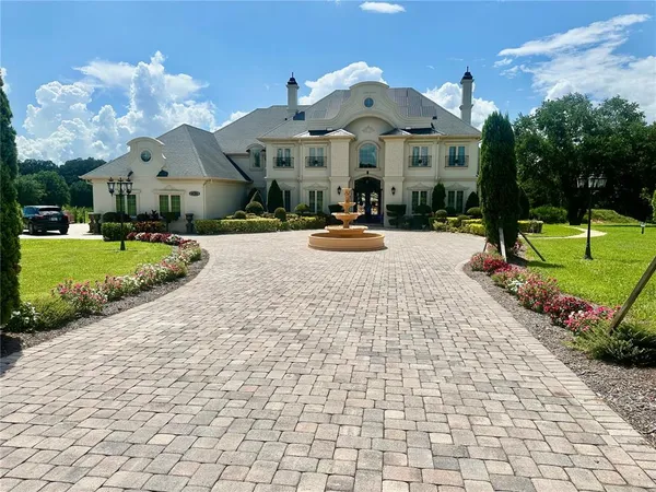 a view of a white house with a yard potted plants and a car park in front of it