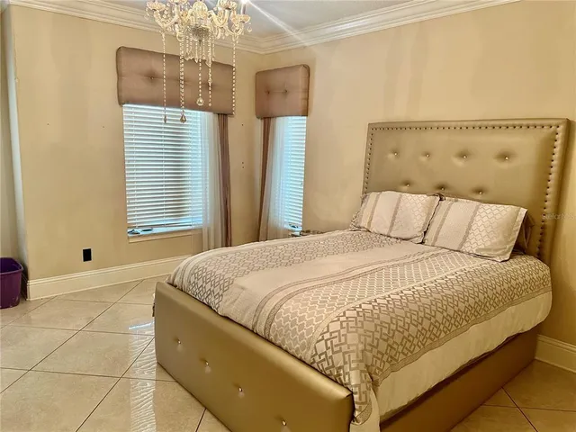 a large bed sitting in a bedroom next to a window and a chandelier