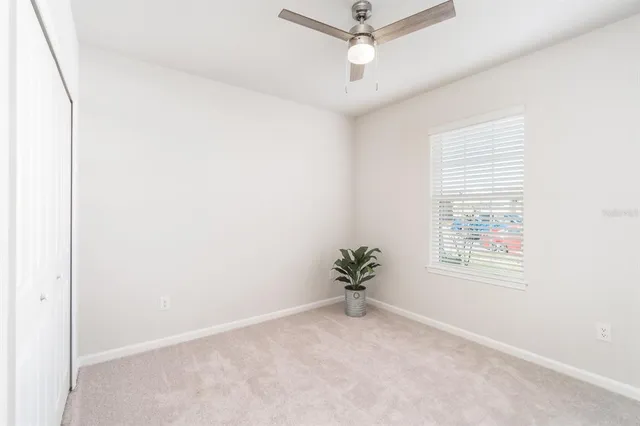 an empty room with a ceiling fan and window