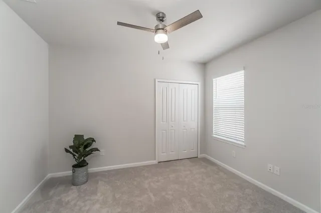 a view of a livingroom with a potted plant a ceiling fan and a window
