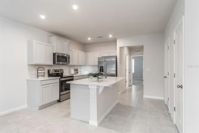 a kitchen with stainless steel appliances a sink a stove a refrigerator cabinets and a window