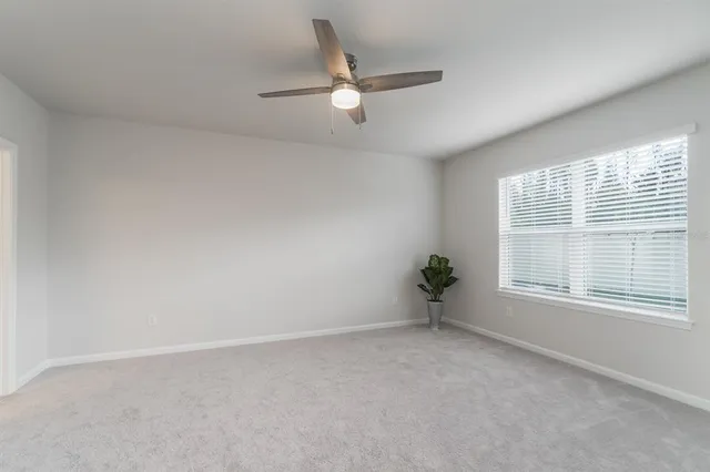 an empty room with a ceiling fan and windows