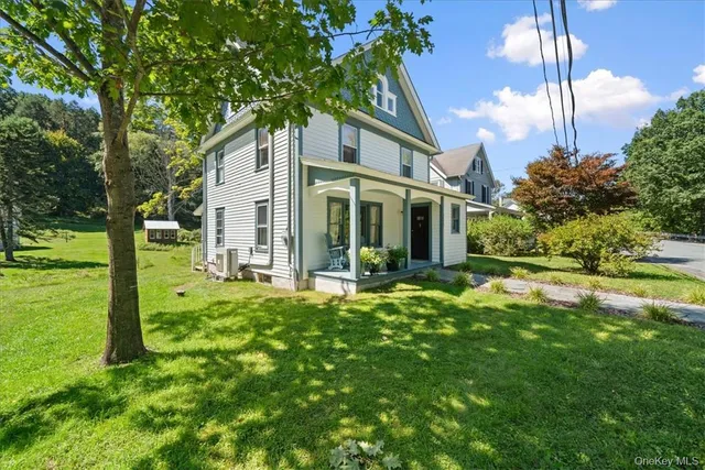 a backyard of a house with table and chairs plants and large tree