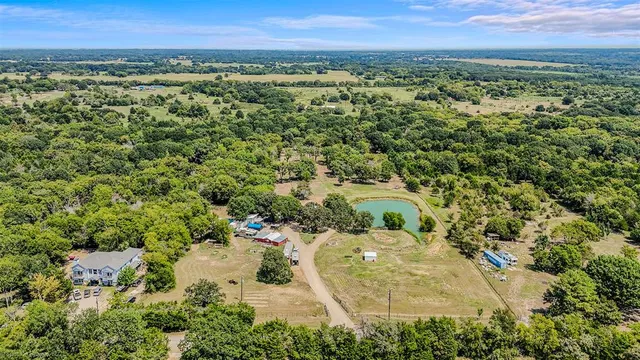 an aerial view of a residential houses with outdoor space and trees