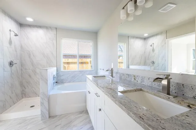 a bathroom with a granite countertop tub sink and mirror