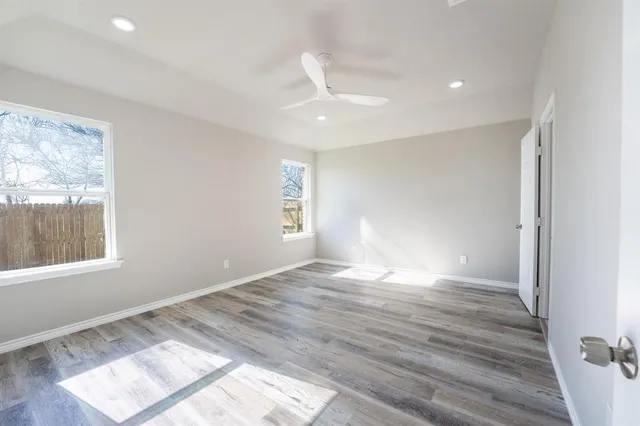 a view of empty room with wooden floor and fan