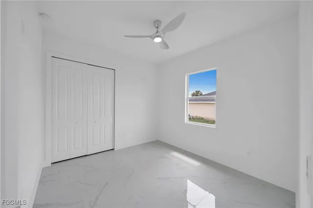 an empty room with a window and a ceiling fan