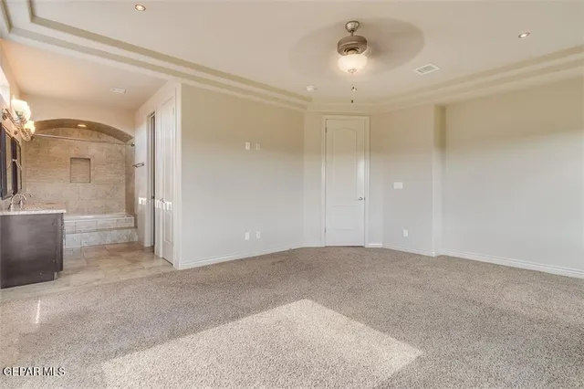 an empty room with chandelier fan and windows
