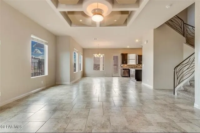a view of an empty room with a kitchen and a window