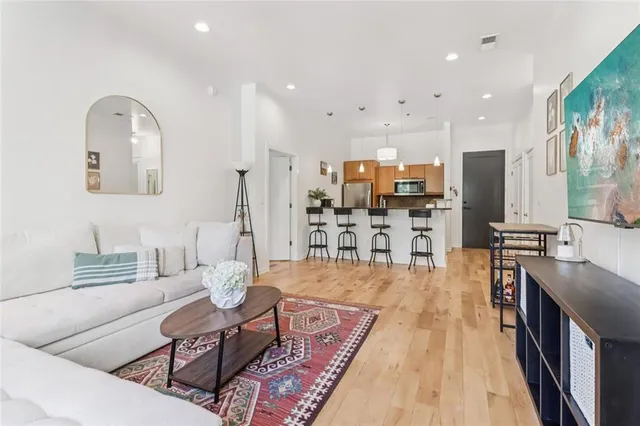 a living room with stainless steel appliances furniture a rug and a kitchen view