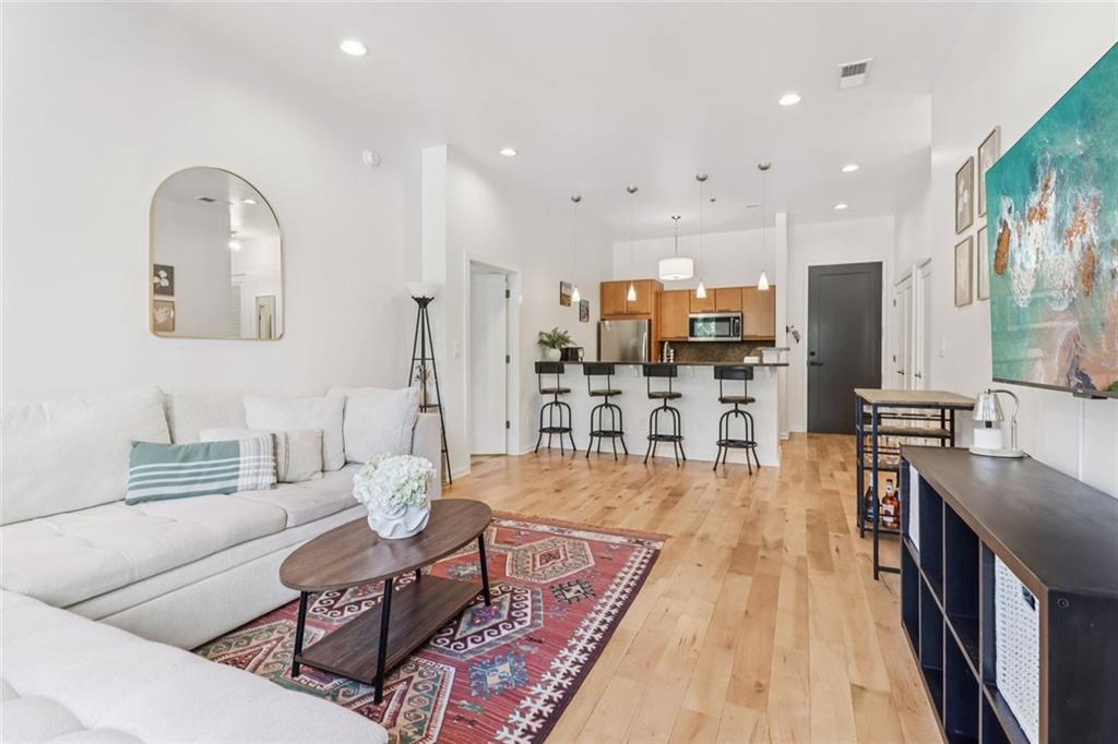 a living room with stainless steel appliances furniture a rug and a kitchen view