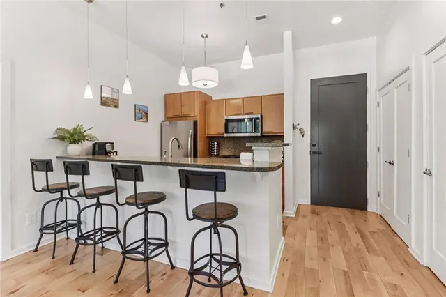 a kitchen with stainless steel appliances kitchen island granite countertop a dining table chairs and a refrigerator