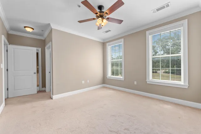 an empty room with chandelier fan and windows