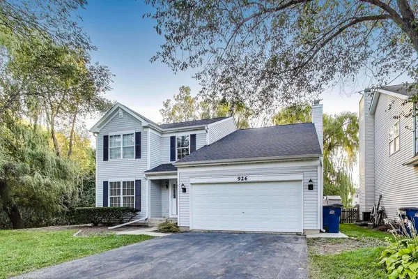 a view of a white house with a yard and large tree