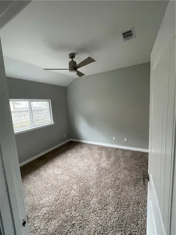 an empty room with windows and fan