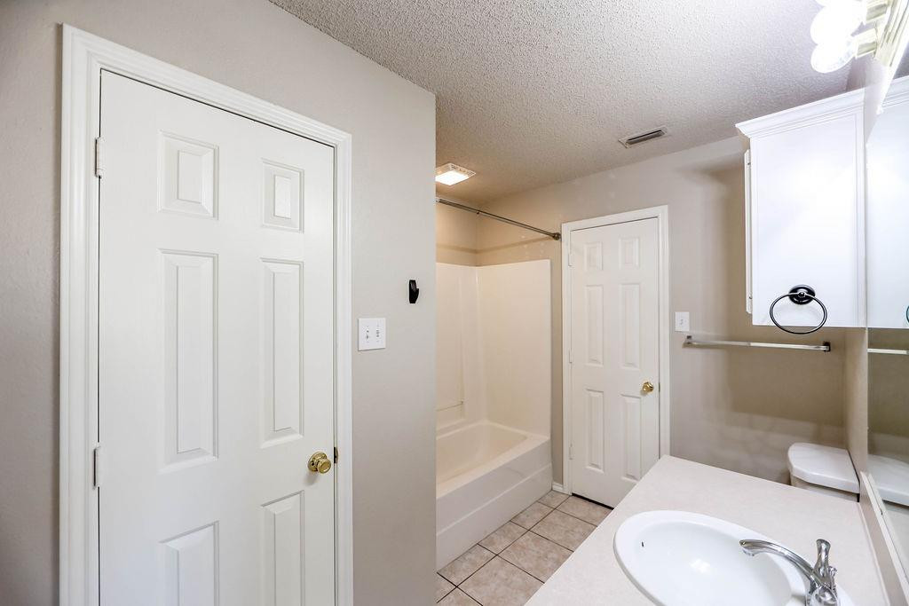 6536 7th Street Lubbock, TX 79416 - Photo 13 of 23 a bathroom with a toilet a sink and shower