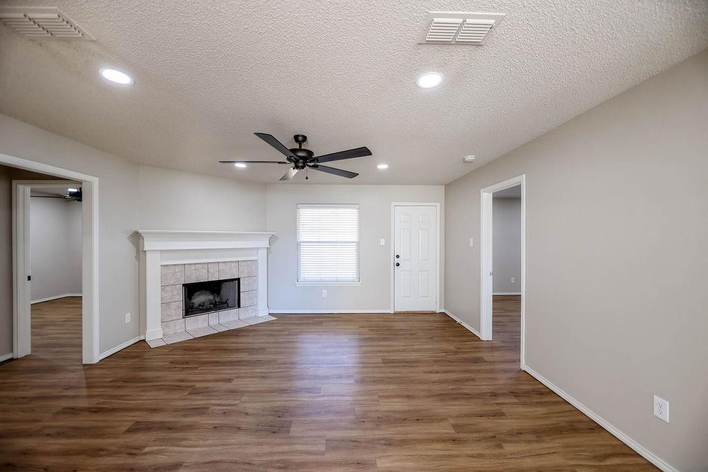 6536 7th Street Lubbock, TX 79416 - Photo 3 of 23 an empty room with wooden floor fireplace and windows