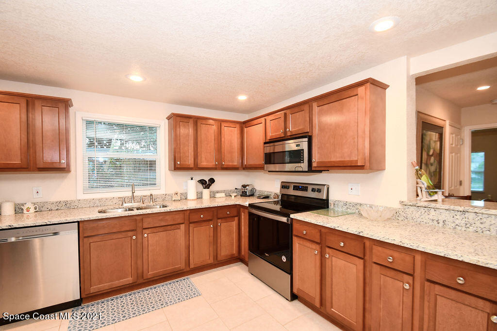 1461 Creel Road Northeast Palm Bay, FL 32905 - Photo 3 of 20 a kitchen with stainless steel appliances granite countertop a sink stove and cabinets