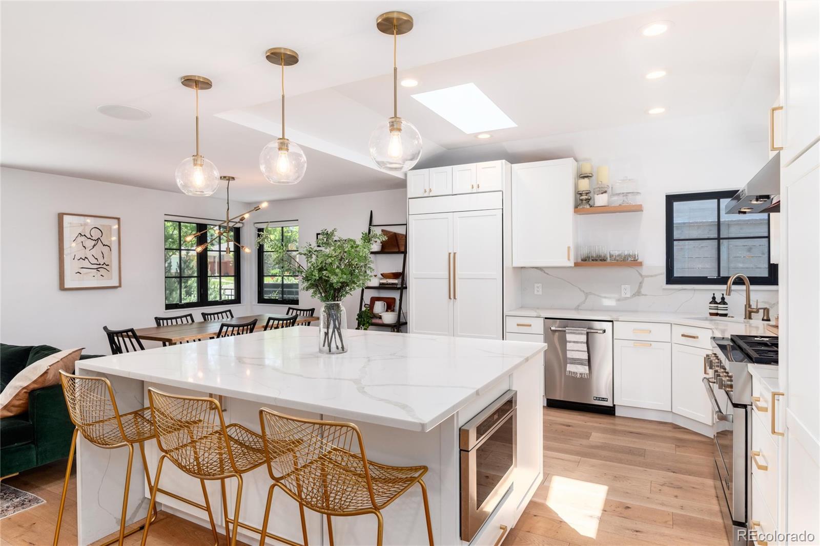 1065 South Monroe Street Denver, CO 80209 - Photo 6 of 32 a kitchen with stainless steel appliances kitchen island granite countertop a stove a refrigerator a oven a sink a dining table and chairs with wooden floor