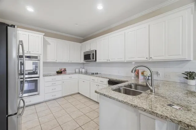a kitchen with granite countertop white cabinets and stainless steel appliances
