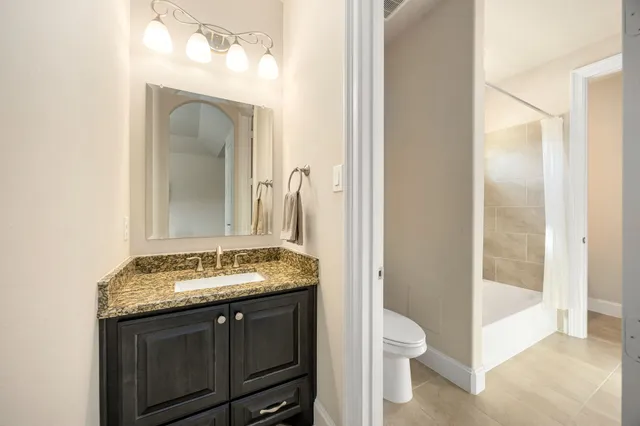 a bathroom with a granite countertop sink a toilet and a mirror