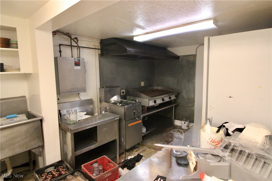 15580 Rittman Road Rittman, OH 44270 - Photo 9 of 11 Kitchen featuring concrete floors, a textured ceiling, and wall chimney exhaust hood