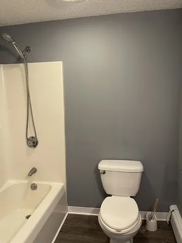 a white toilet sitting next to a bath tub and a shower