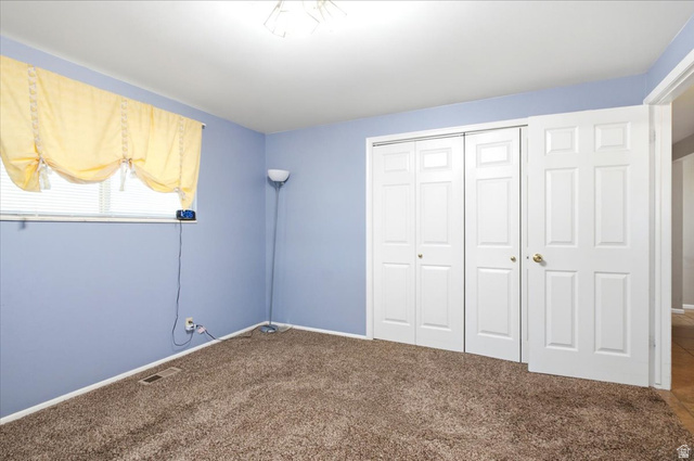 7050 South 260 East Midvale, UT 84047 - Photo 19 of 28 Plush brown carpeting throughout, complemented by a window with horizontal blinds and a ceiling-mounted light fixture