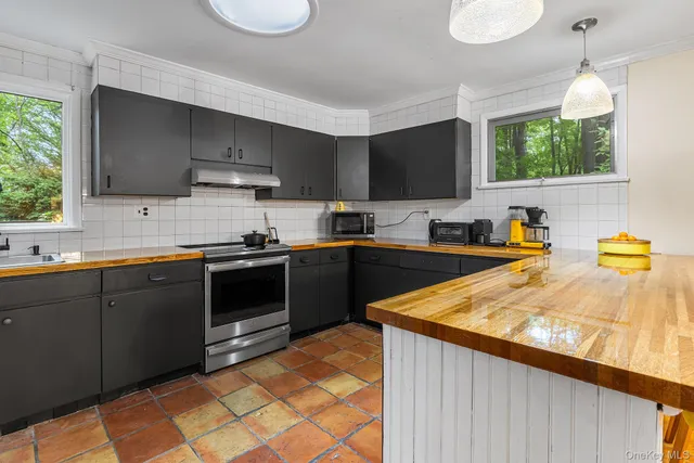 a kitchen with a sink a stove cabinets and wooden floor