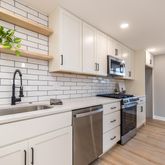 a kitchen with stainless steel appliances a sink stove and wooden floor