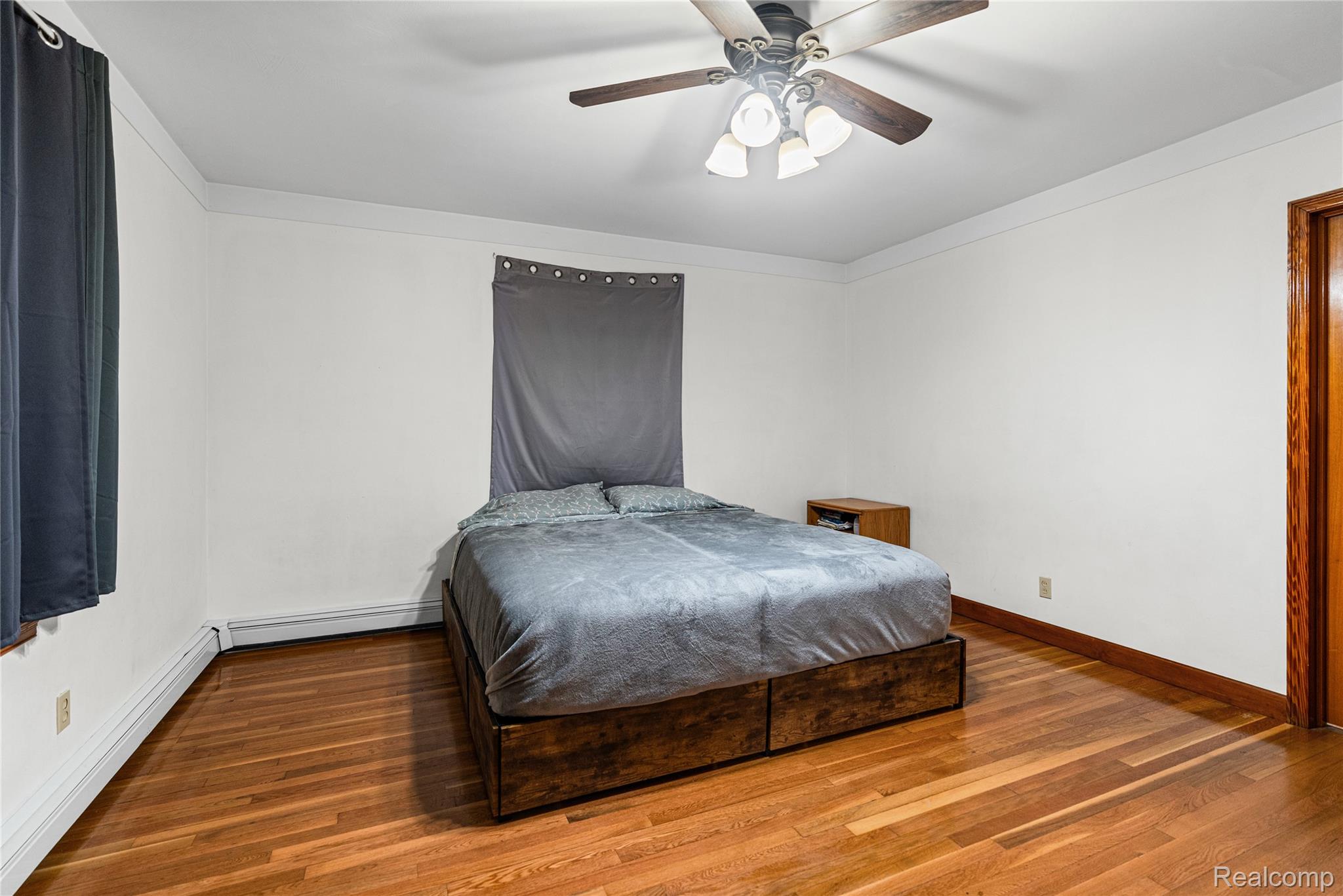 6383 Lapeer Road Burton, MI 48509 - Photo 17 of 44 Bedroom featuring a baseboard radiator, ornamental molding, hardwood / wood-style floors, ceiling fan, and a baseboard heating unit