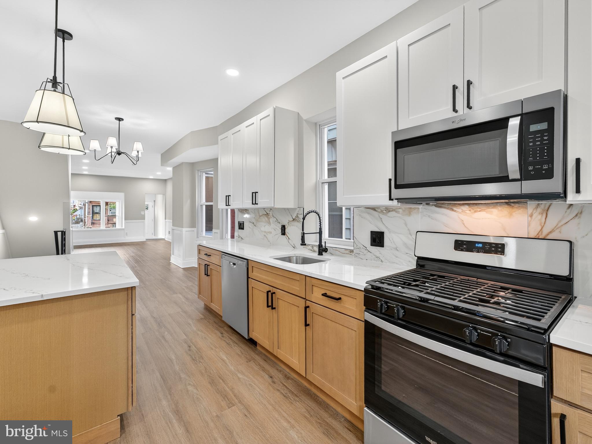 5736 Spruce Street Philadelphia, PA 19139 - Photo 4 of 32 a kitchen with stainless steel appliances kitchen island granite countertop a stove top oven a sink dishwasher and a microwave oven with white cabinets