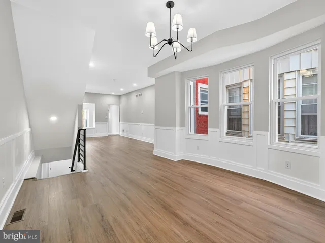 a view of empty room with wooden floor and windows