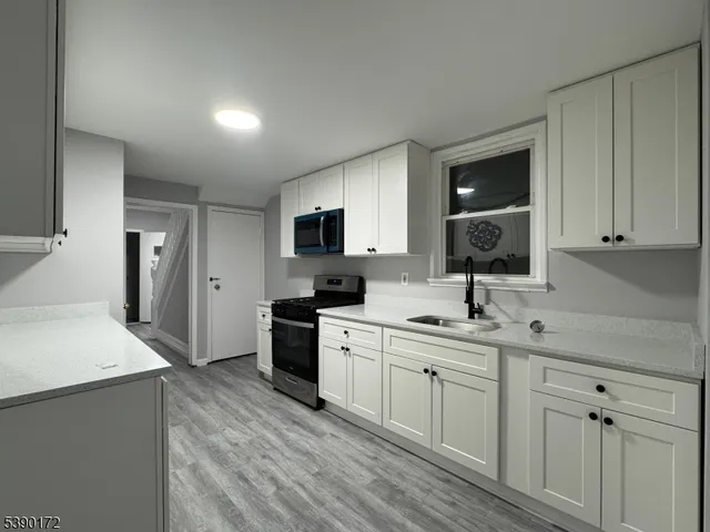 a kitchen with a sink white cabinets and stainless steel appliances